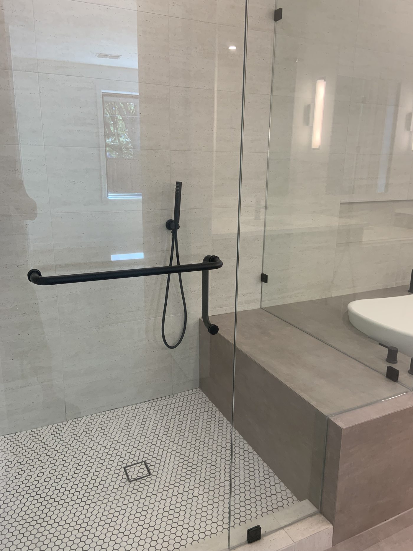 Frameless glass walk-in shower with hexagon floor tile and bench