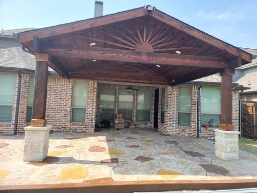Stained wood covered patio with vaulted ceiling and stone columns